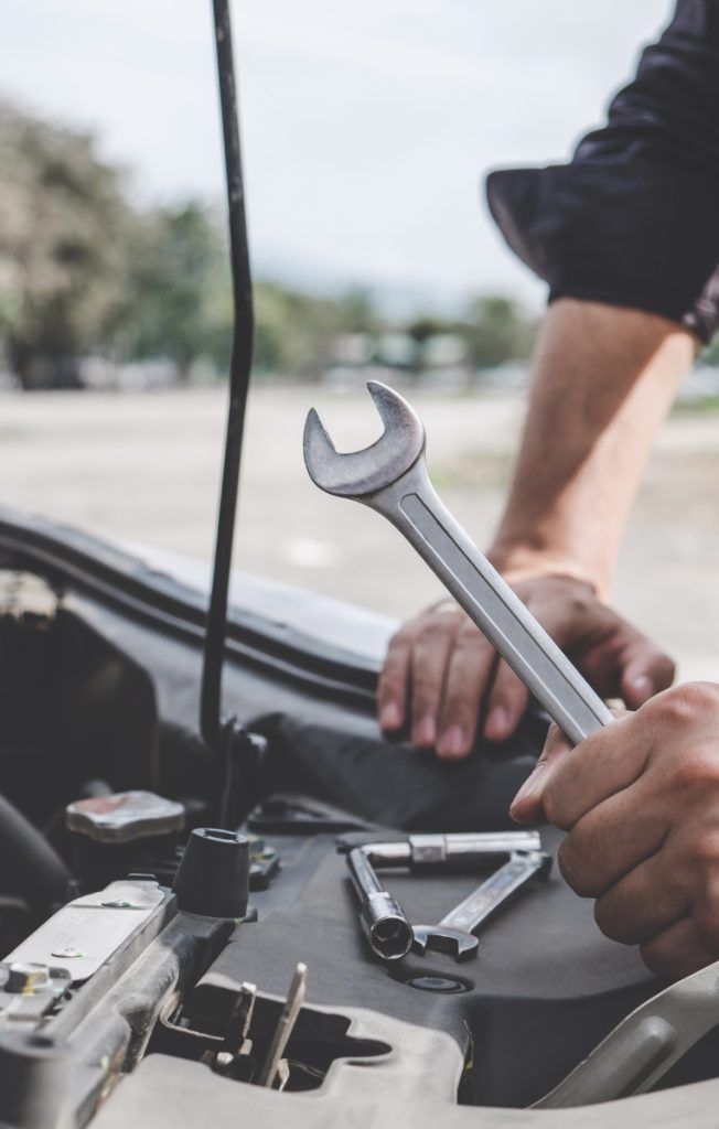 Mechanic holding a spanner looking over a vehicle engine - Repairs Glasgow